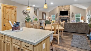 A spacious kitchen with wooden cabinetry, a central island, and a dining area with a table and chairs. - Raintree at Roslyn Ridge - Cozy Retreat (Ronald)
