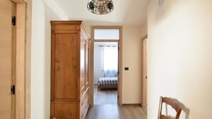 Un couloir avec des armoires en bois, un lit recouvert d’une couverture à carreaux et une chaise.