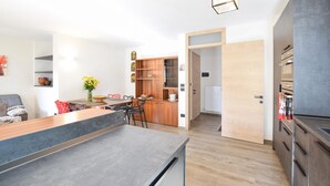 Une cuisine moderne avec des meubles en bois, un four encastré et un coin repas comprenant une table et des chaises en bois.