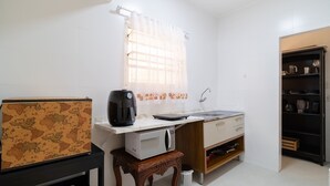Una cocina compacta equipada con microondas, hervidor y un lavamanos pequeño.