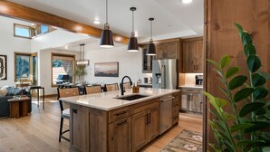 Una cocina amplia con armarios de madera, una isla grande e iluminación colgante.