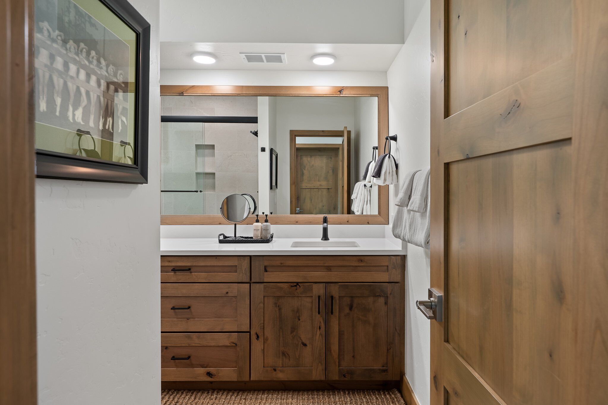 Un bagno con un mobile vanitario in legno, uno specchio grande e un lavandino bianco.