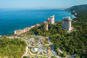 Um resort costeiro com vários edifícios altos, um porto de iates e vegetação exuberante.