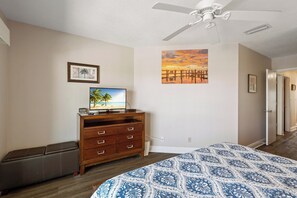 A bedroom with a bed, a dresser, a television, and a ceiling fan.