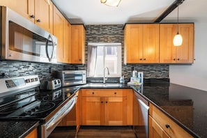 A modern kitchen with wooden cabinets, a stainless steel stove, and a black countertop.