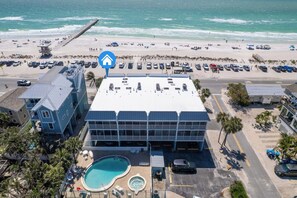 A hotel with a pool, beach view, and parking lot.