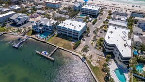An aerial view of a coastal hotel with multiple buildings, a marina, and a beach. - Sunset Soul at Pelican Cove Unit 8 by SeaBreeze Vacation (Bradenton Beach)