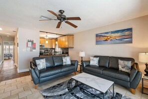 A living room with a black leather sofa, a coffee table, and a ceiling fan.