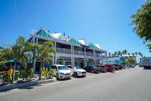A building with a green and white facade, a balcony, and a parking lot with several cars.