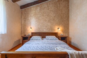 A bedroom with a wooden bed, two bedside tables, and wall-mounted lamps.