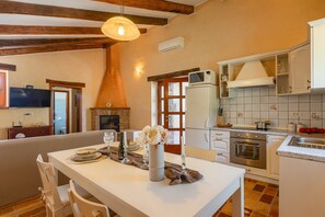 A dining area with a table set for two, a fireplace, and a kitchen with modern appliances. - Villa Fiore (Istria - Žminj) (Žminj)