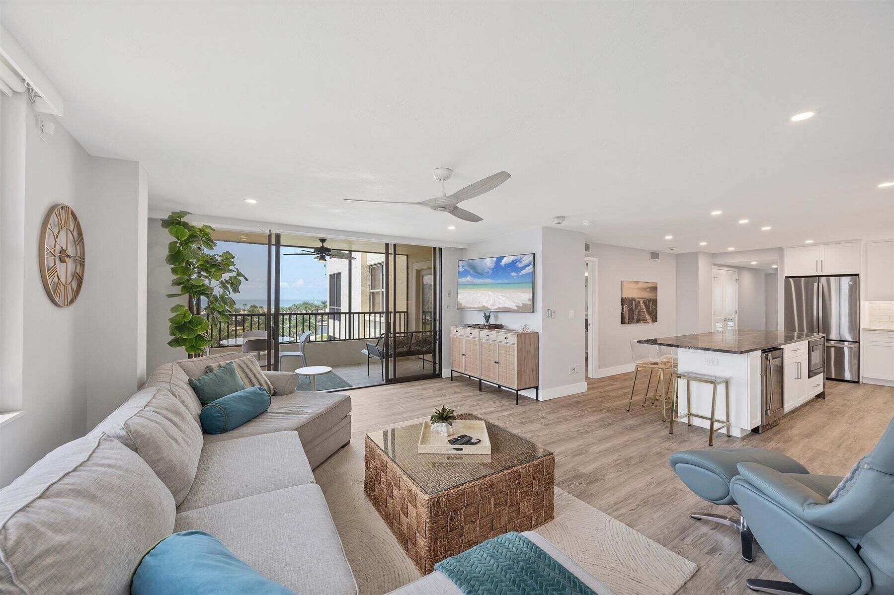 A modern living room with a large sofa, a coffee table, and a view of the ocean through large windows.