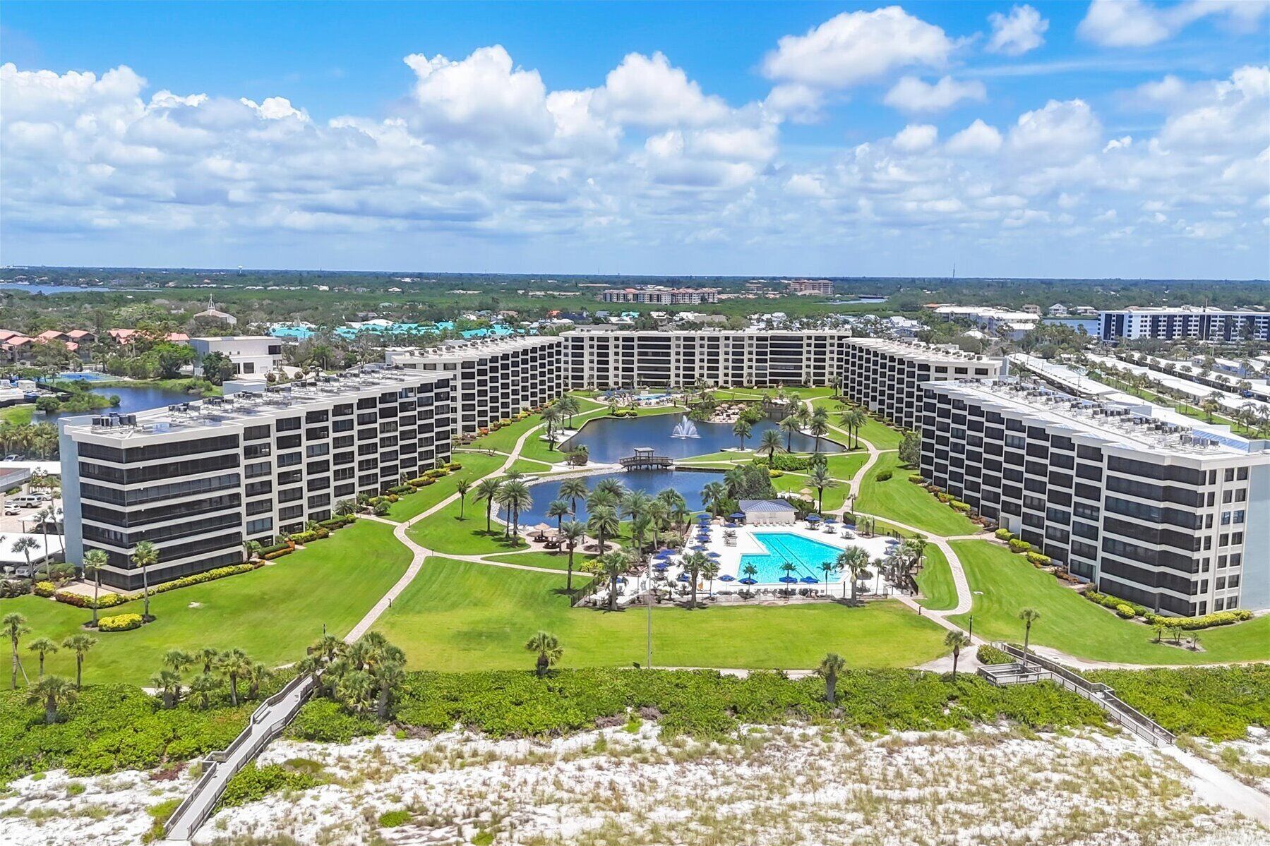 A large hotel with multiple buildings, a central pool, and surrounding greenery.