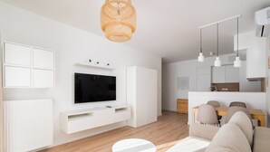 A modern living room with a flat-screen TV, white furniture, and a wooden floor. - Wola Signature Apartment (Warszawa)