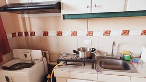 A compact kitchen with a gas stove, a washing machine, and a sink.