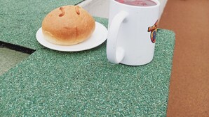 A table with a loaf of bread and a mug on a rooftop terrace with a view of a historic building.