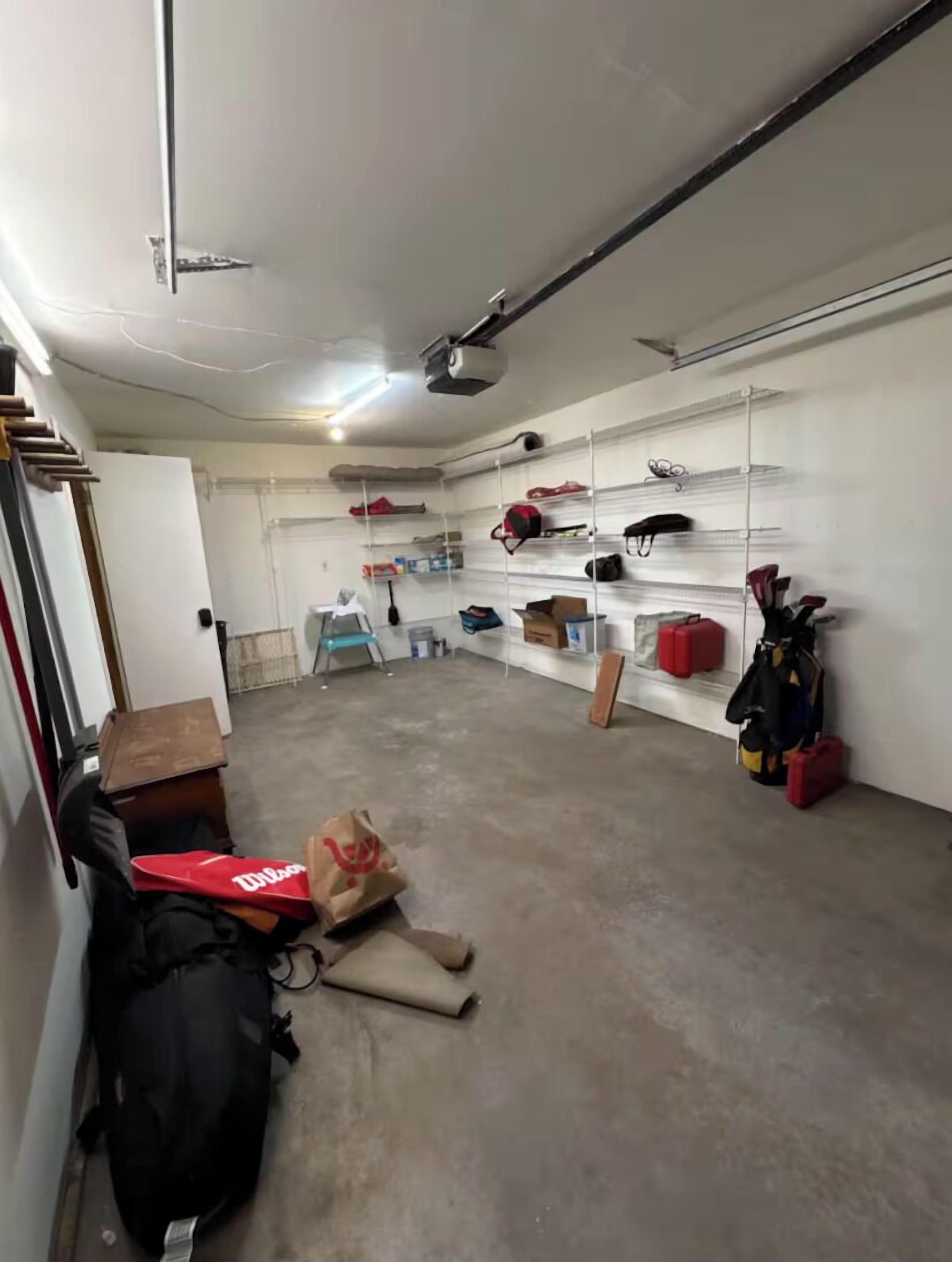 A storage room with shelves, a ceiling fan, and various items on the floor.