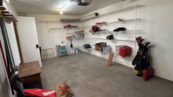 A storage room with shelves, a ceiling fan, and various items on the floor.