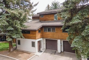 Una casa a due piani con facciata in legno, un garage e una strada privata.