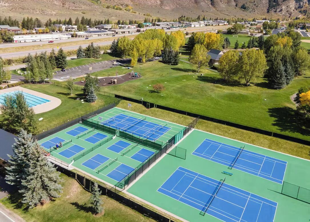 Un complesso di campi da tennis con più campi, un'area di parcheggio e vegetazione circostante.