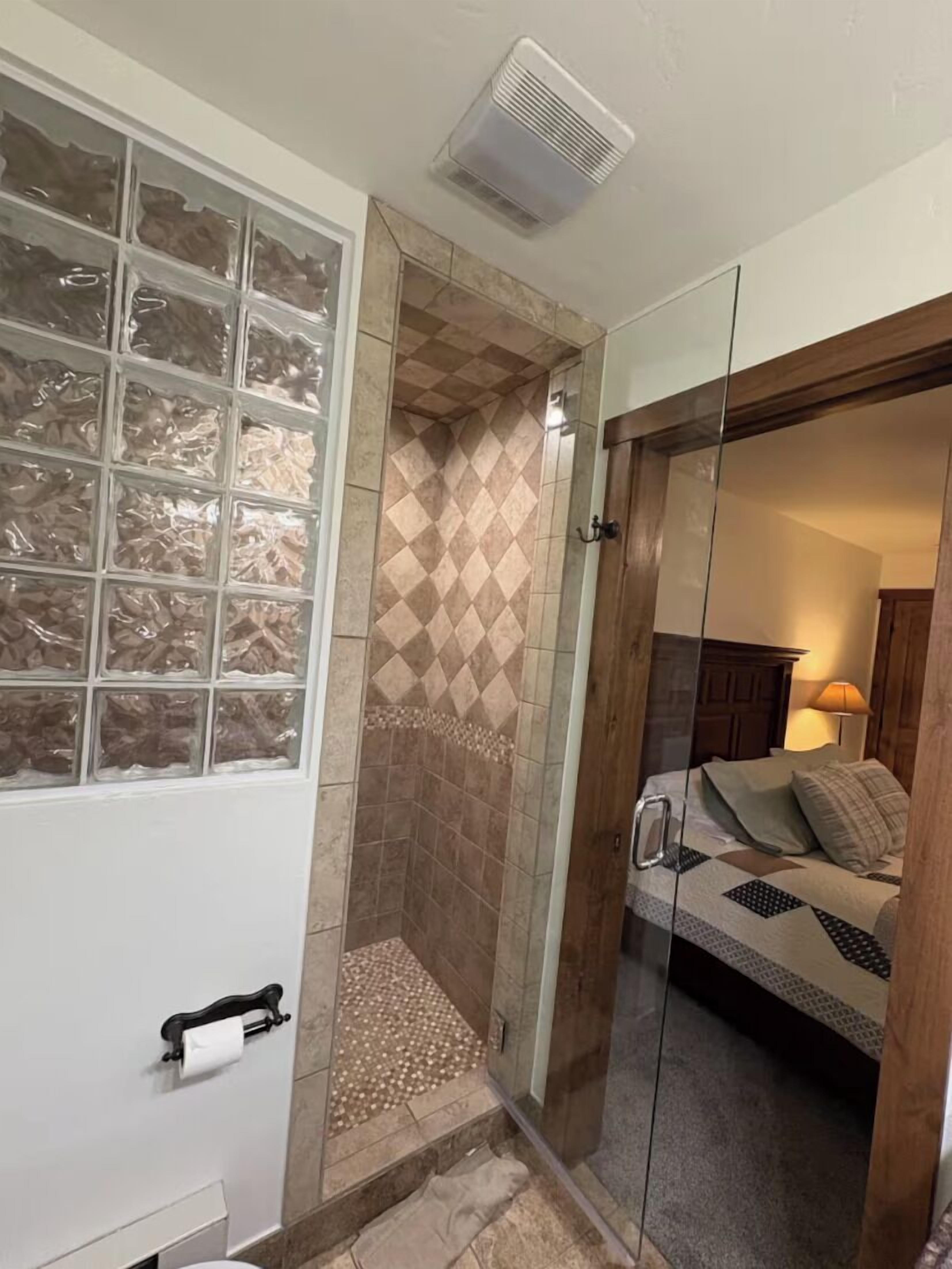 Un baño con cabina de ducha de vidrio, inodoro y lavamanos.