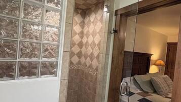 Un baño con cabina de ducha de vidrio, inodoro y lavamanos.
