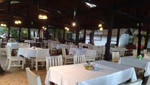 An outdoor dining area with white tables and chairs, covered by a roof with hanging lights. - Kokotel Khao Lak Lighthouse (Takua Pa)