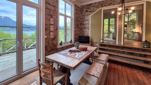 A cozy room with a wooden table, benches, and a TV. Large windows offer a view of the outdoors. - Awesome home in Vaksdal with house sea view (Vaksdal)