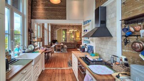 A spacious kitchen with wooden floors, large windows, and a central island. - Awesome home in Vaksdal with house sea view (Vaksdal)