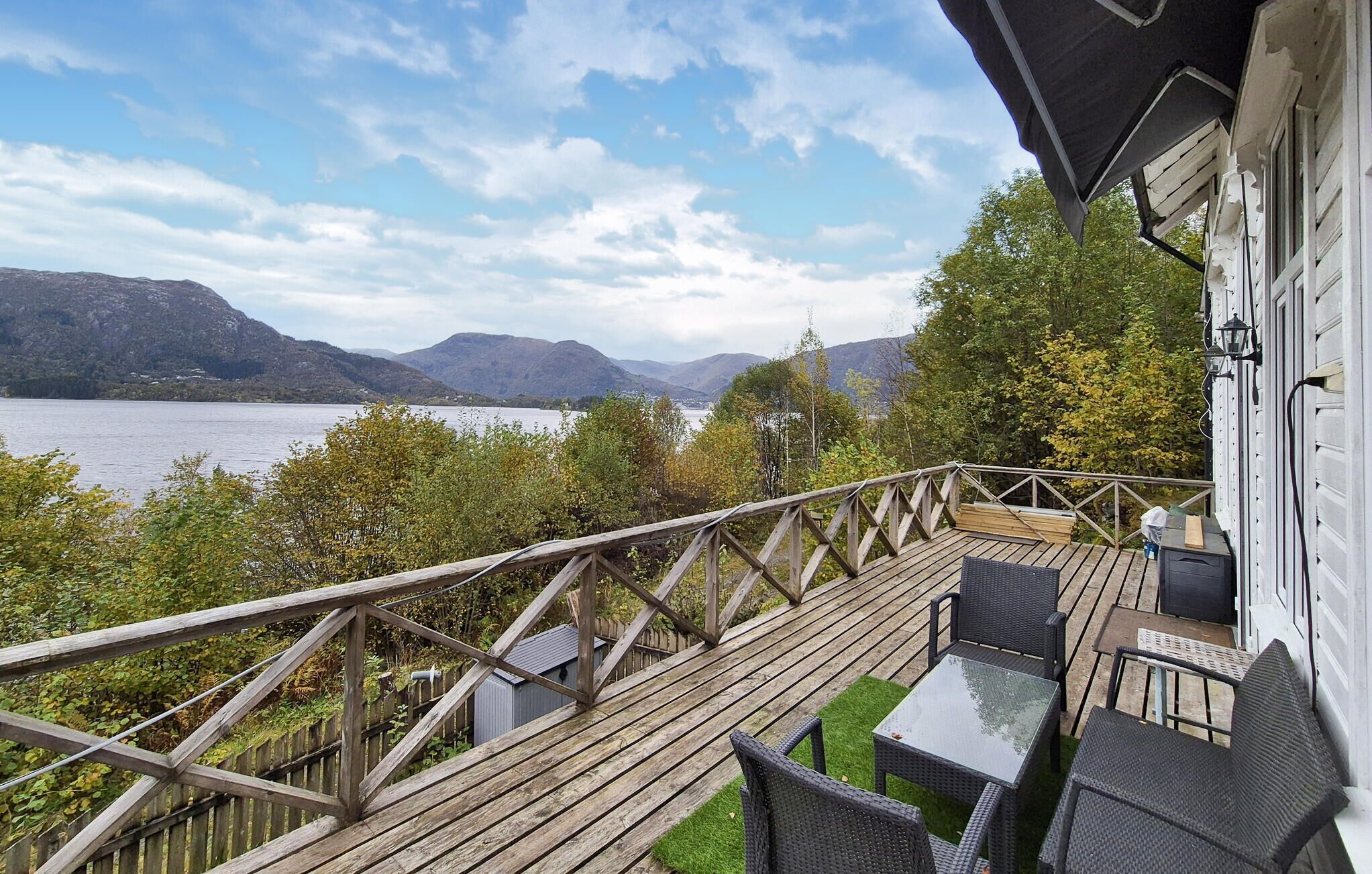 A wooden deck with outdoor furniture overlooking a lake and mountains.