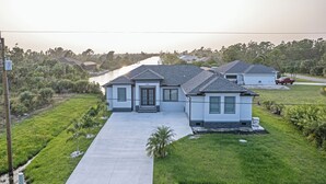 Een modern huis met twee verdiepingen, een voortuin, oprit en een rivier op de achtergrond.
