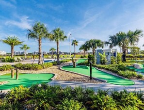 Mini golf course with green turf, landscaped paths and palm trees at the resort.