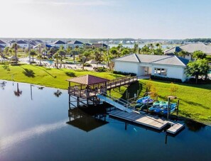 View of the lake, covered boat dock with kayaks and the community clubhouse.