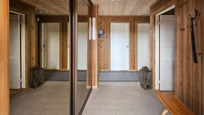 A hallway with wooden walls and doors, a bench, and a small table with a lantern. - 3 bedroom awesome home in Flå (Flå)