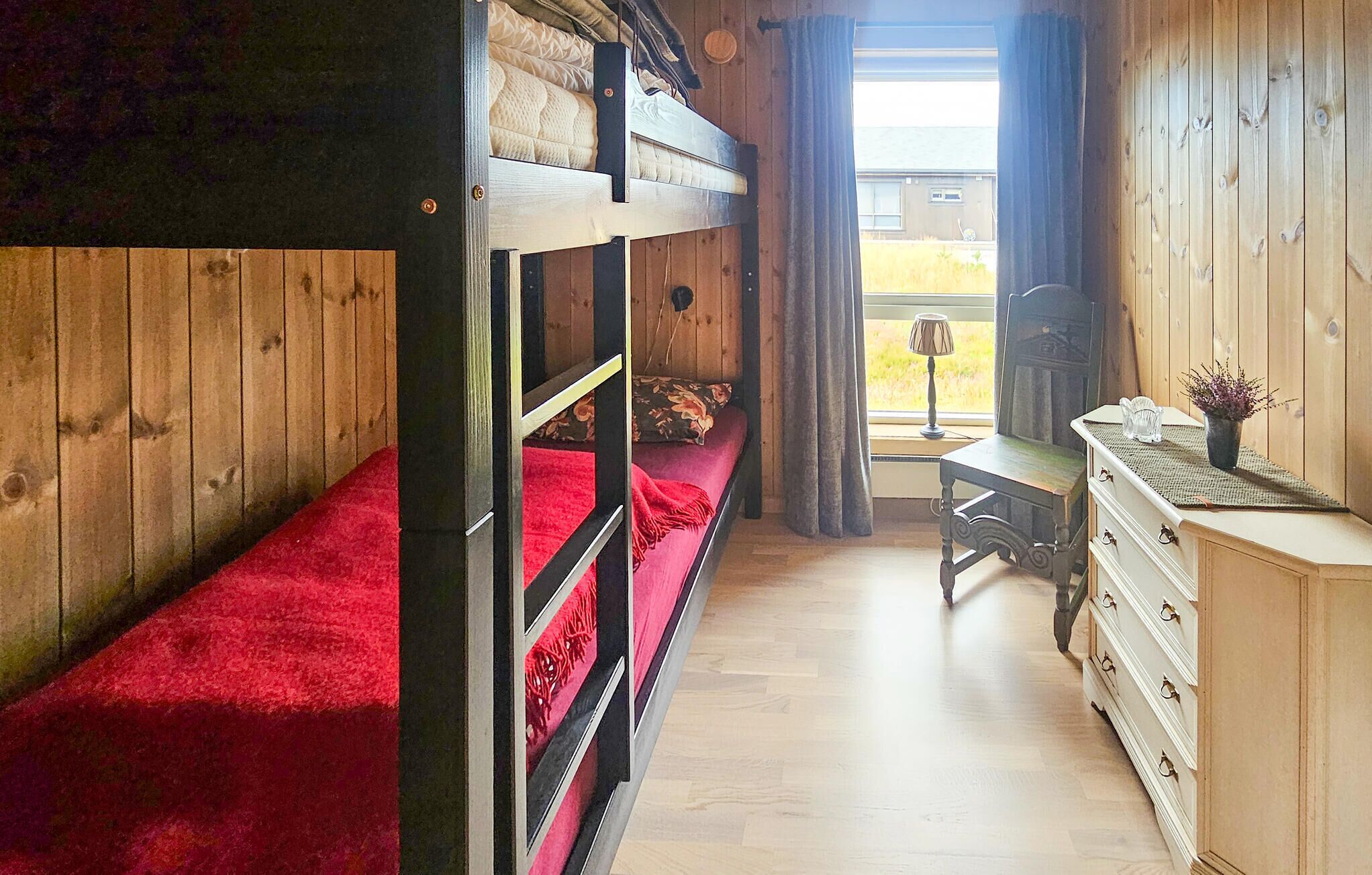 Une petite pièce comprenant un lit superposé, un bureau et une commode.
