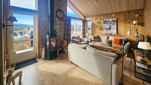 A cozy living room with a fireplace, a sofa, a coffee table, and a view of the outdoors. - 3 bedroom awesome home in Flå (Flå)