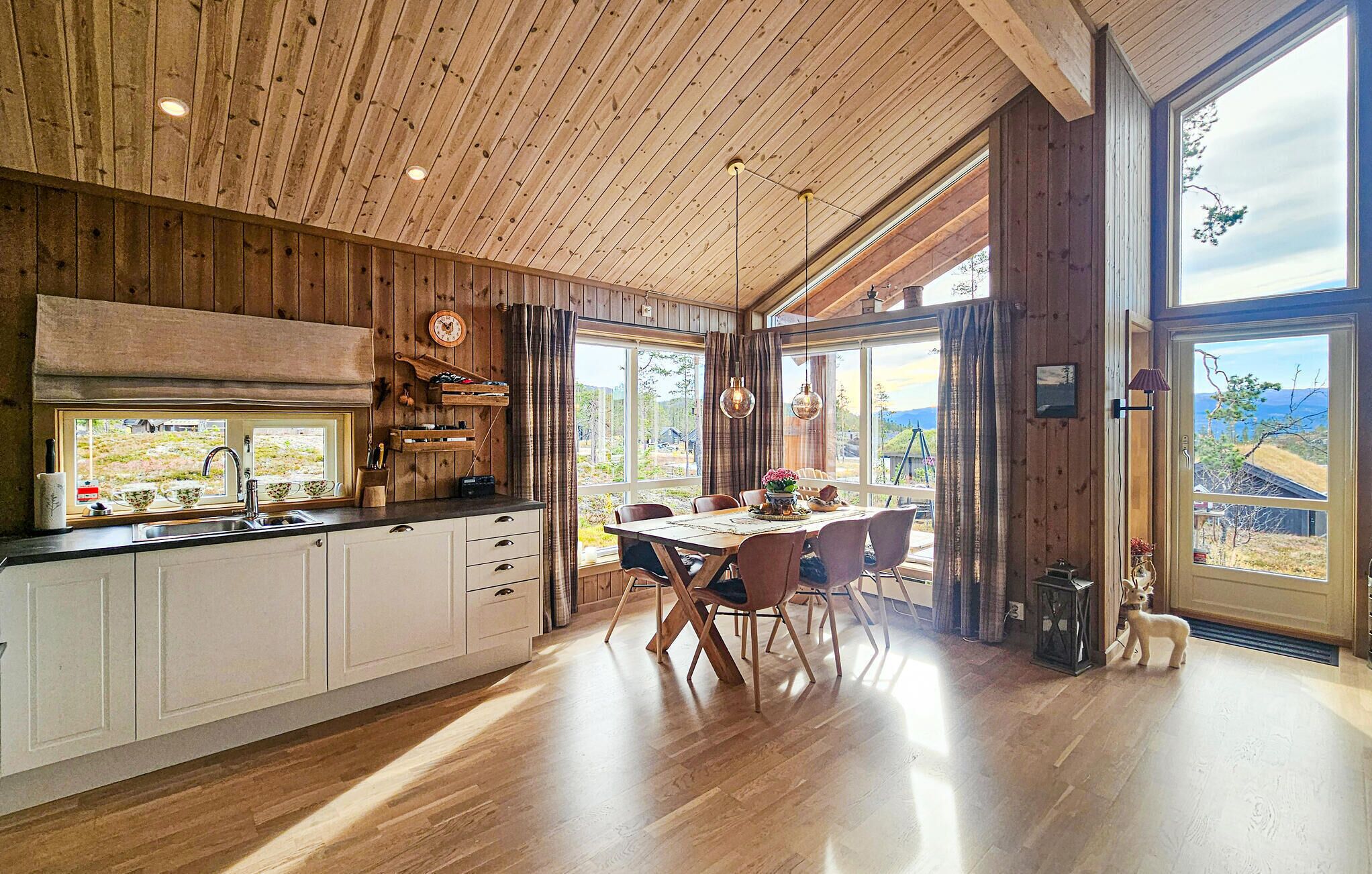 Une cuisine spacieuse, dotée de meubles en bois, d’une grande fenêtre et d’un coin repas avec une table et des chaises.