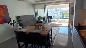 A modern kitchen with a dining area, a large window, and a view of the city. - Modern 1 bedder with river views in West End (West End)