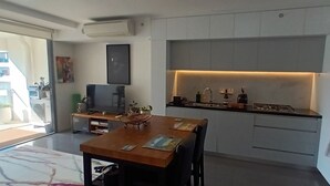 A modern kitchen with a dining area, built-in cabinets, and a large window. - Modern 1 bedder with river views in West End (West End)