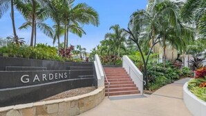 A staircase leading to a building labeled 'GARDENS' with a stone wall and palm trees. - Modern 1 bedder with river views in West End (West End)