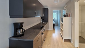 Une cuisine moderne avec des meubles de couleur sombre, une machine à café noire et un plan de travail en bois.