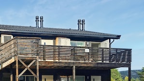 Un bâtiment à deux étages doté d’une terrasse en bois et de deux cheminées sur le toit.