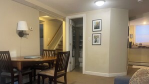 Un comedor con mesa y sillas de madera, una lámpara y una escalera que lleva a un segundo piso.