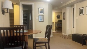 Un comedor con una mesa y sillas de madera, una lámpara y cuadros en las paredes.