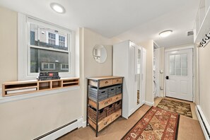A hallway with a built-in bookshelf, a mirror, a door, and a patterned rug.