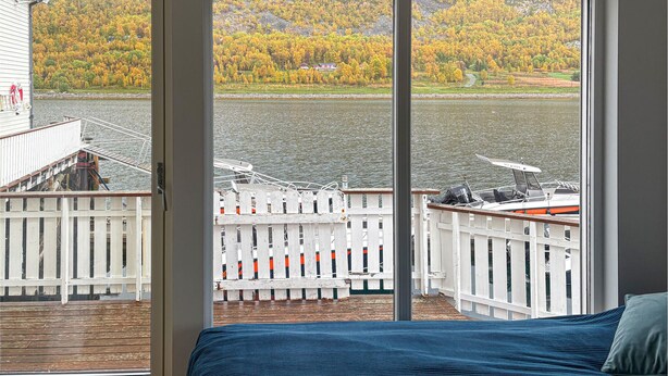 A room with a large sliding glass door leading to a dock with boats.