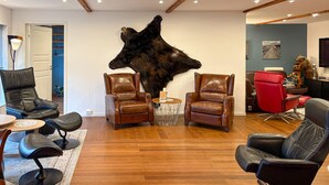 A living room with leather chairs, a large bear head sculpture, and a wooden floor.