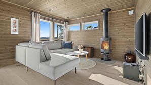 A modern living room with a grey sofa, a TV, and a wood-burning stove. - Nice home in Sannidal with lake view (Sannidal)