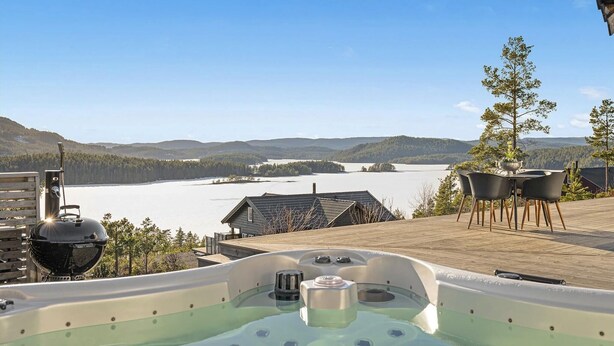 A hot tub on a wooden deck overlooking a lake with mountains in the background. - Nice home in Sannidal with lake view (Sannidal)