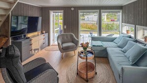 A modern living room with a television, sofa, and armchair. - 4 bedroom awesome home in Færvik (Færvik)